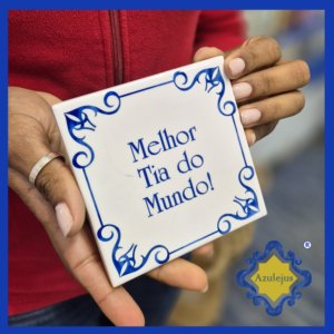 Azulejo nas mãos de uma senhora escrito Melhor Tia do Mundo.
