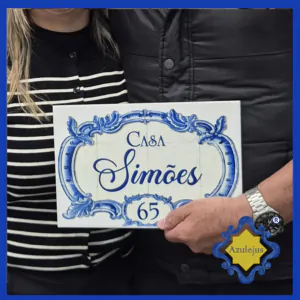 Casal a segurar azulejo com o texto Casa Simões.